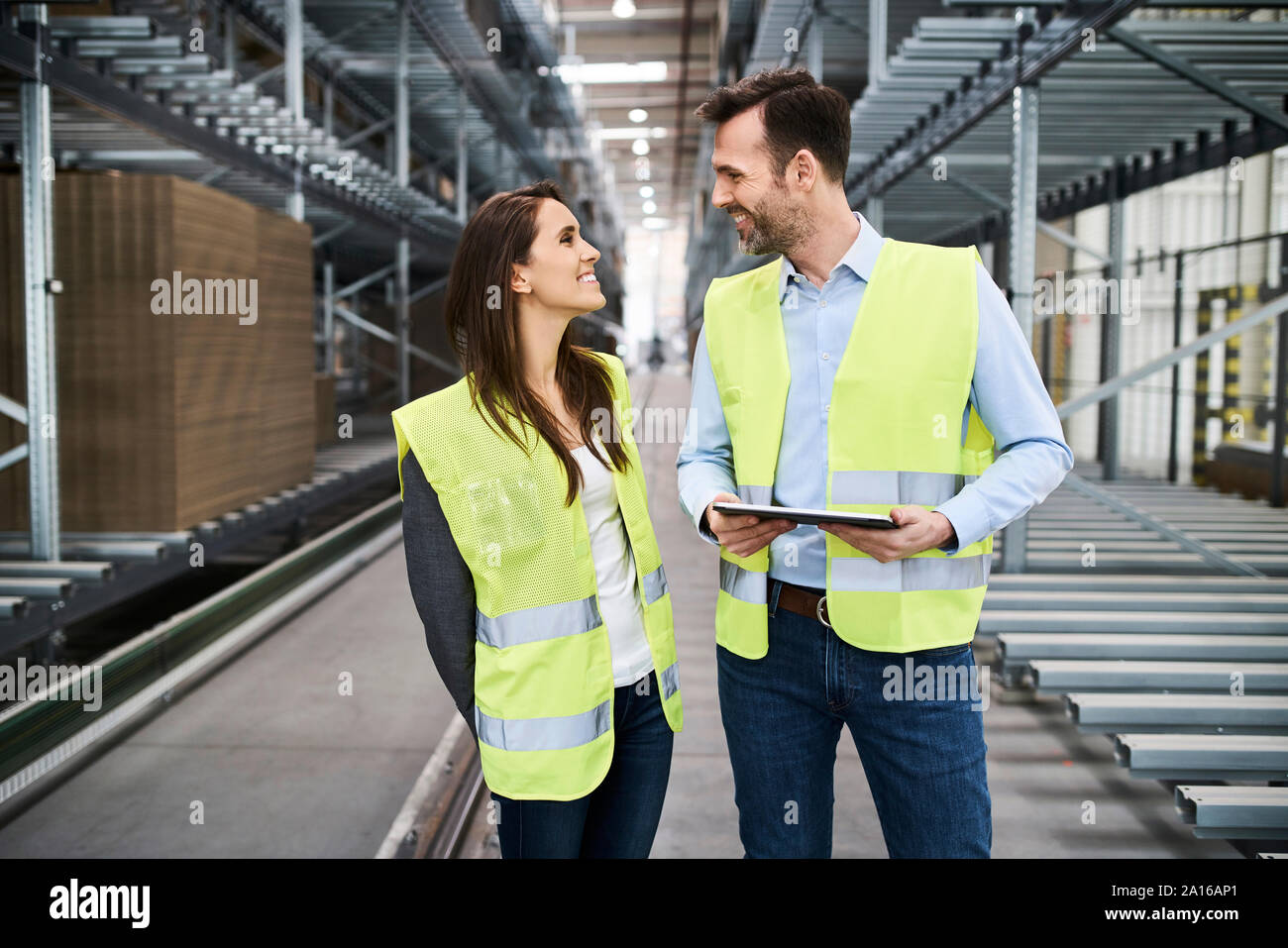 Colleagues wearing reflective vests with tablet in factory Stock Photo