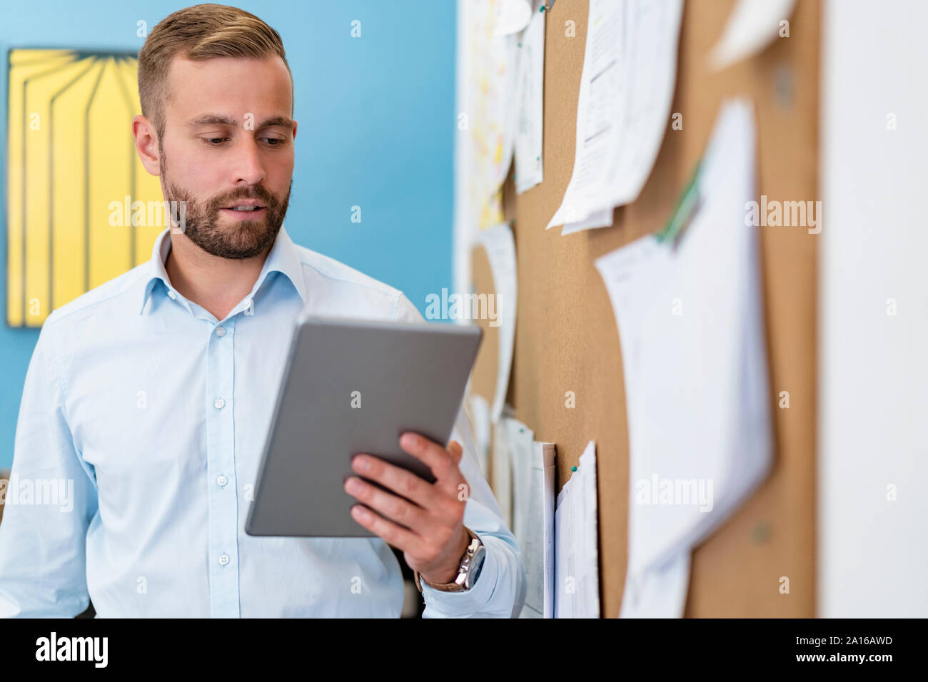 Businessman using tablet at pinboard in office Stock Photo