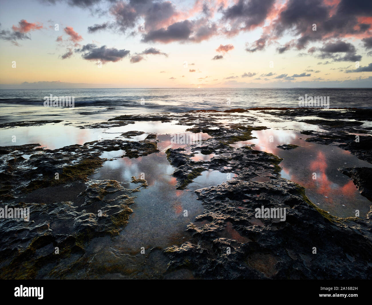 Scenic view of sea against sky seen from rocky beach at Ka'ena Point State Park during sunset Stock Photo