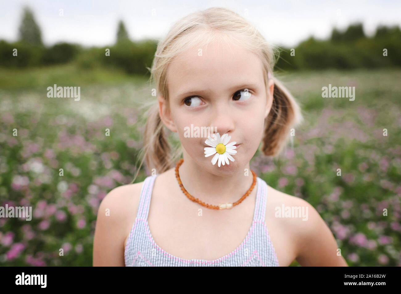 Girl with chamomile flower in her mouth Stock Photo