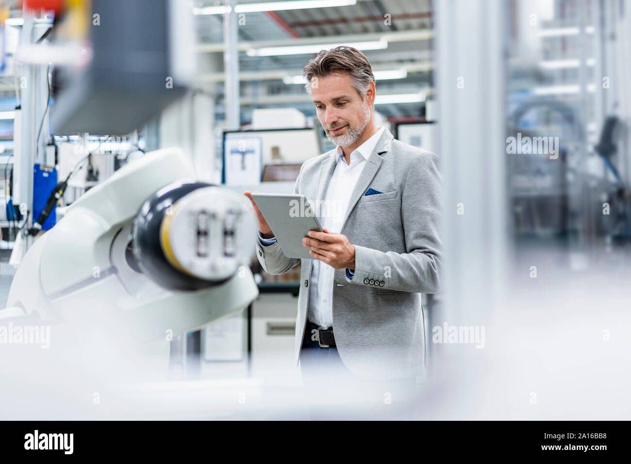 Businessman with tablet at assembly robot in a factory Stock Photo