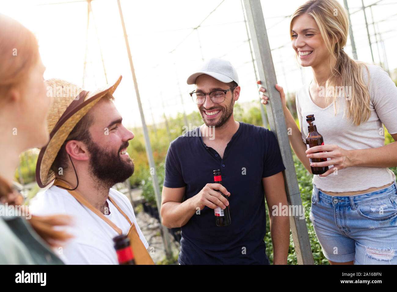 Group of friends drinking beer and enjoying time in the greenhouse Stock Photo