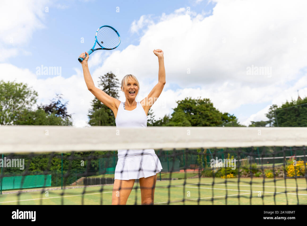 Happy female tennis player celebrating the victory on grass court Stock Photo