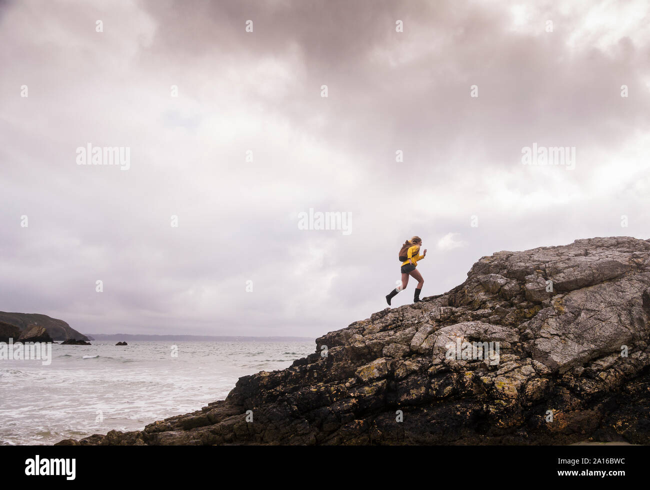 Woman wearing yellow rain jacket walking at the beach Stock Photo - Alamy