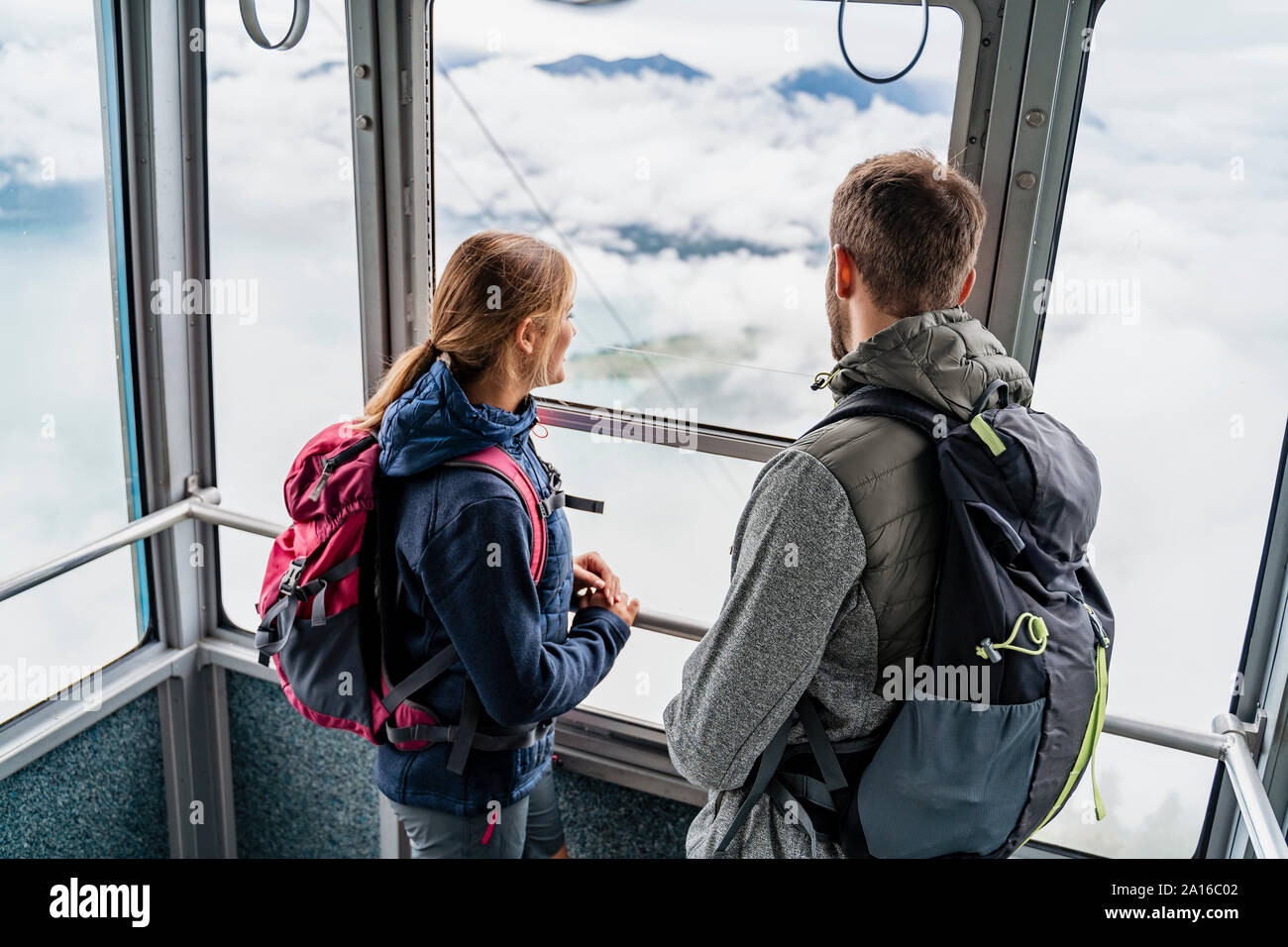 Young couple in a gondola cableway looking out of window, Herzogstand, Bavaria, Germany Stock Photo