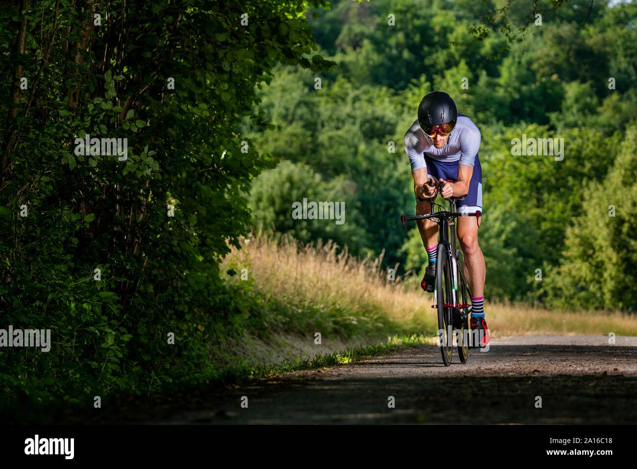 Triathlete riding bicycle on country road, Germany Stock Photo