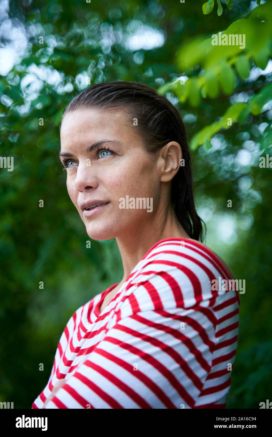 Portrait of pensive woman with wet hair wearing striped top in nature Stock Photo