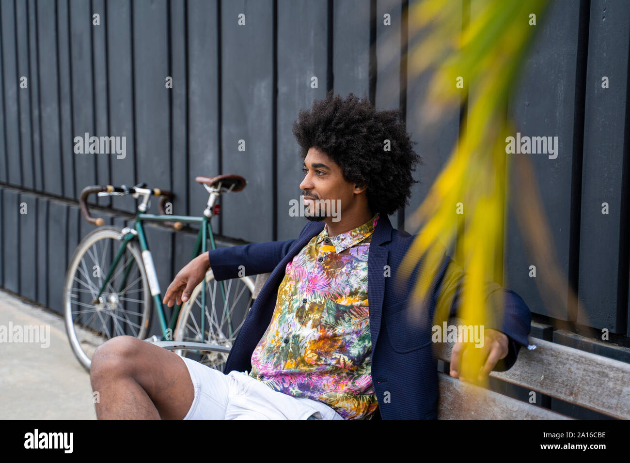 Stylish man with bicycle sitting on a bench Stock Photo