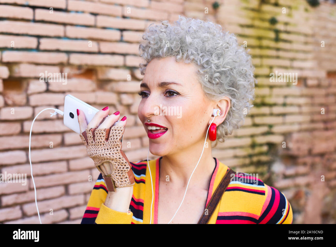 Portrait of pierced mature woman with ear phones on the phone Stock Photo