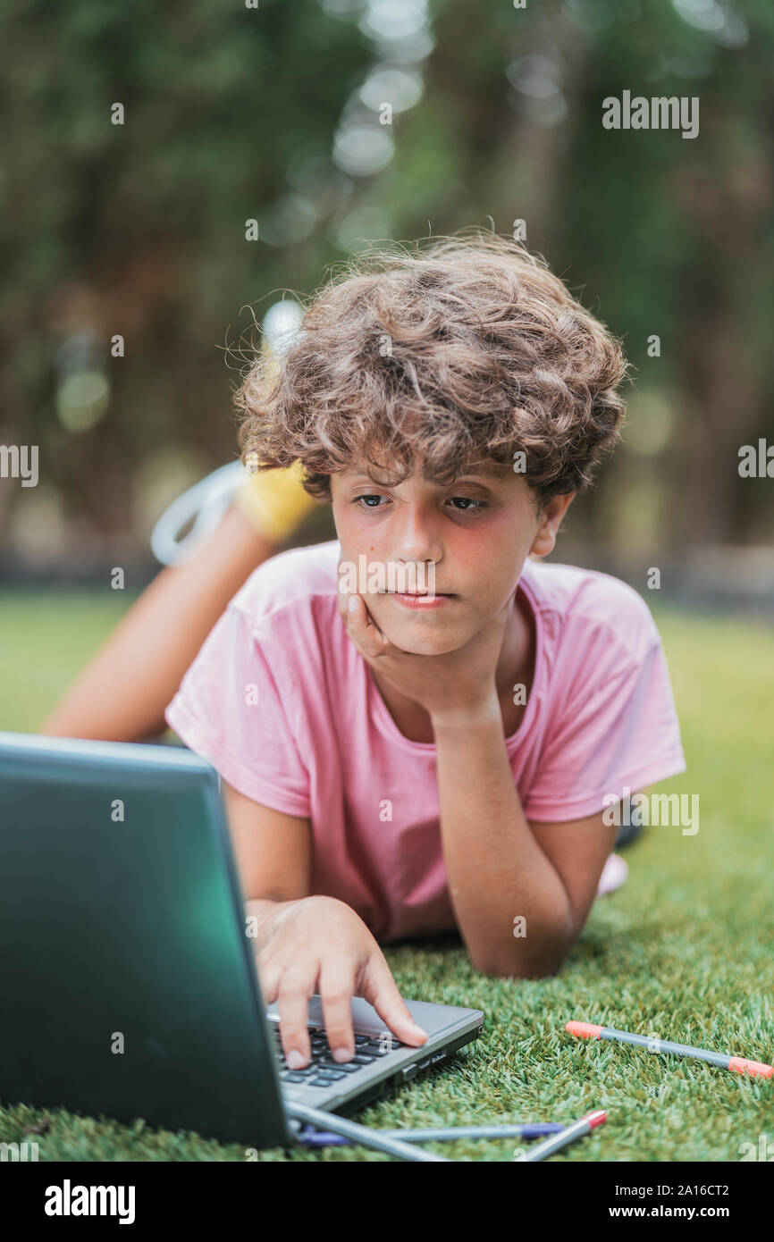 Boy lying in grass using laptop Stock Photo