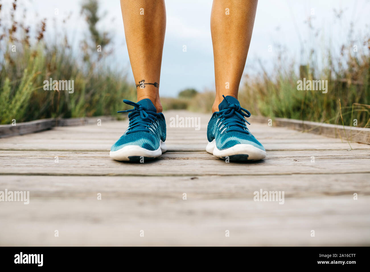 Feet of female jogger standing on wooden boardwalk Stock Photo