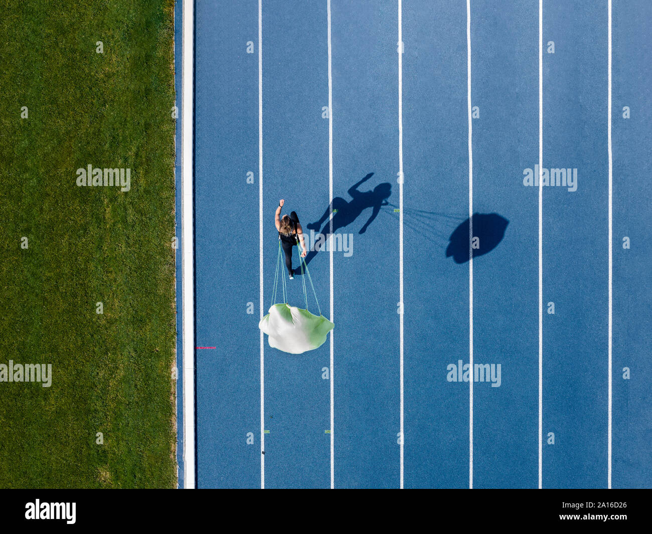 Top view of female runner with parachute on tartan track Stock Photo