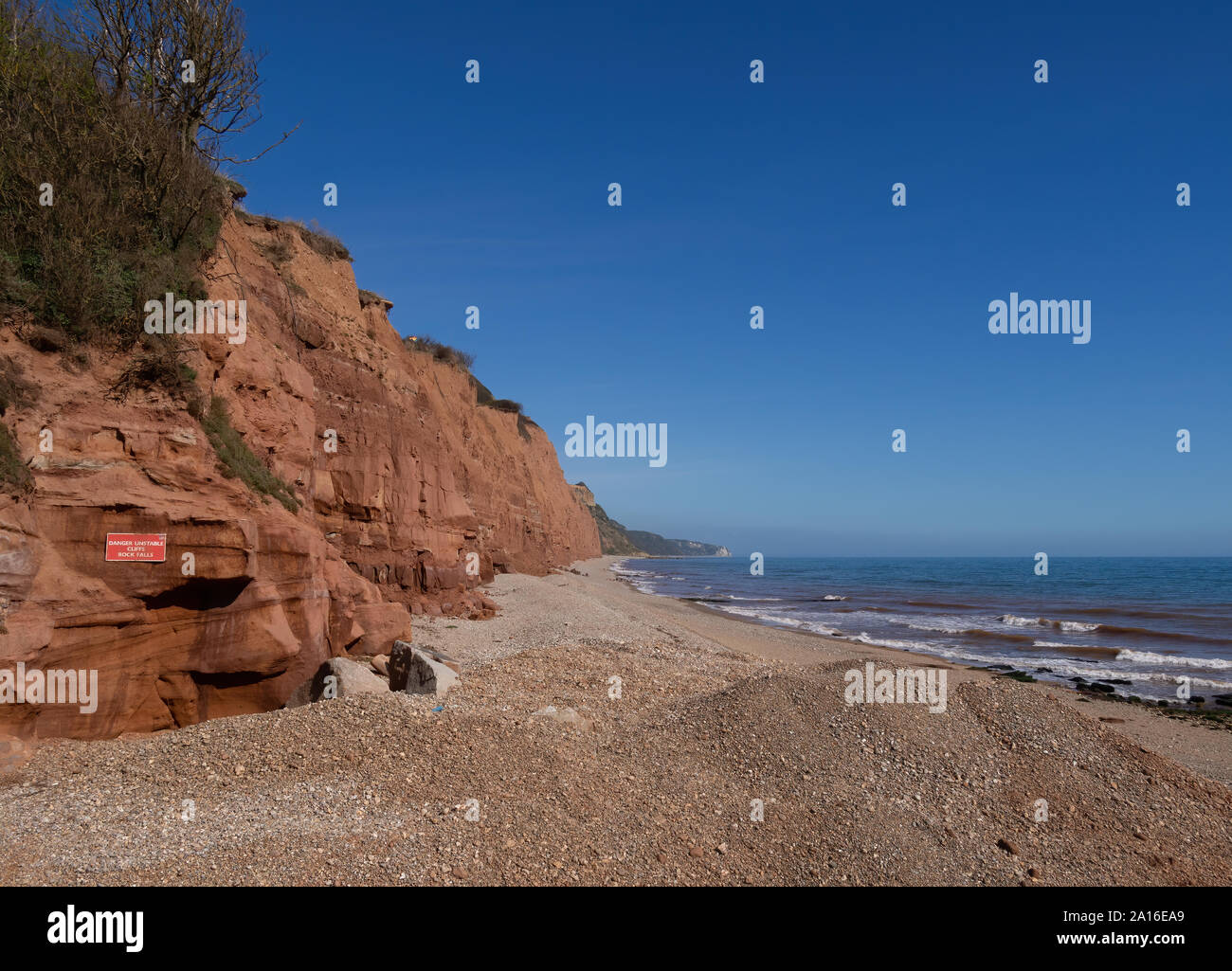 The famous Jurassic Coast red cliffs at Sidmouth, Devon, England. Looking East from Sidmouth Beach with warning of danger of landslides. Stock Photo