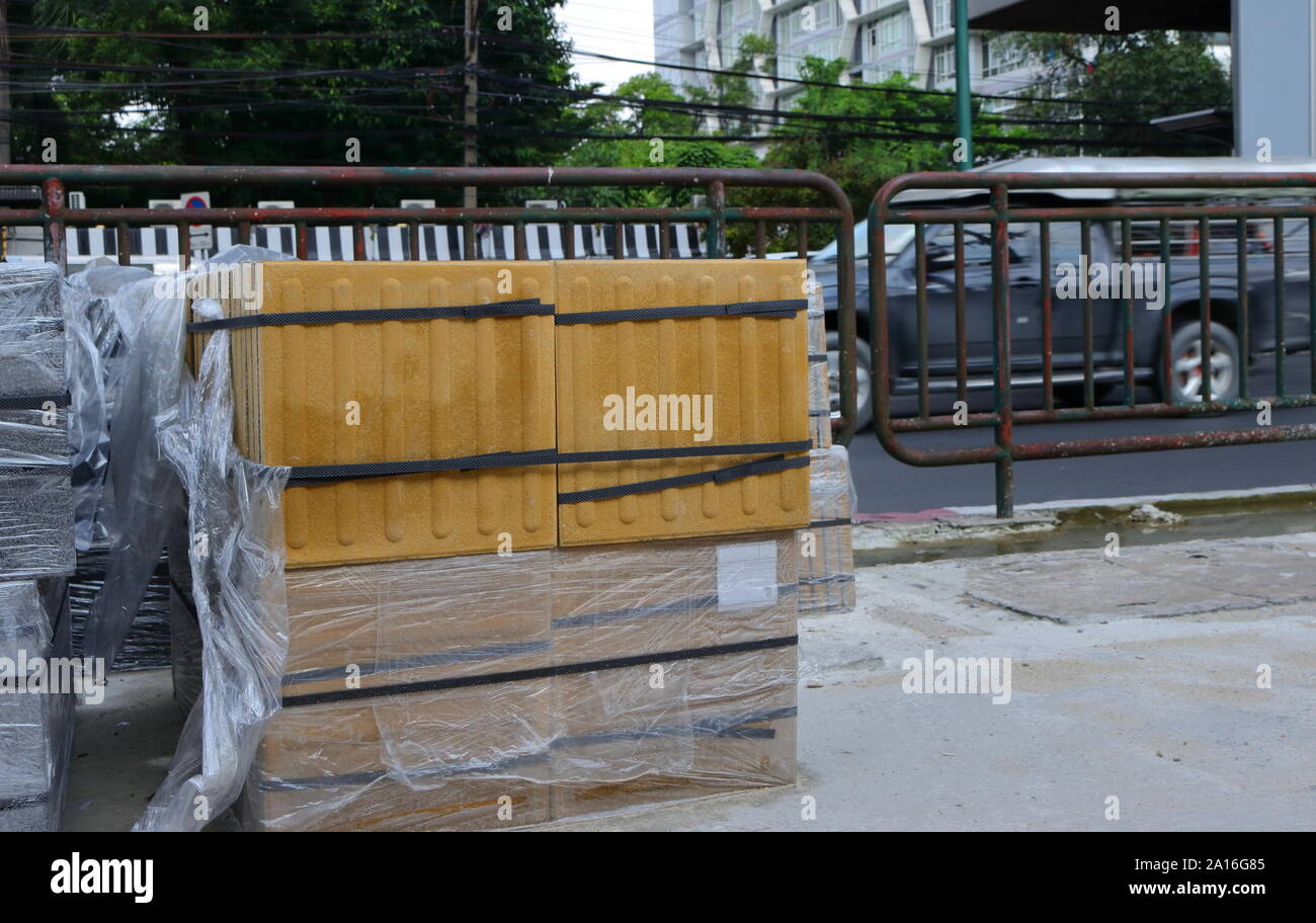 Closeup stack of braille blocks prepared for footpath repairing. Braille blocks are used to assist visually impaired pedestrians, the blocks with stra Stock Photo