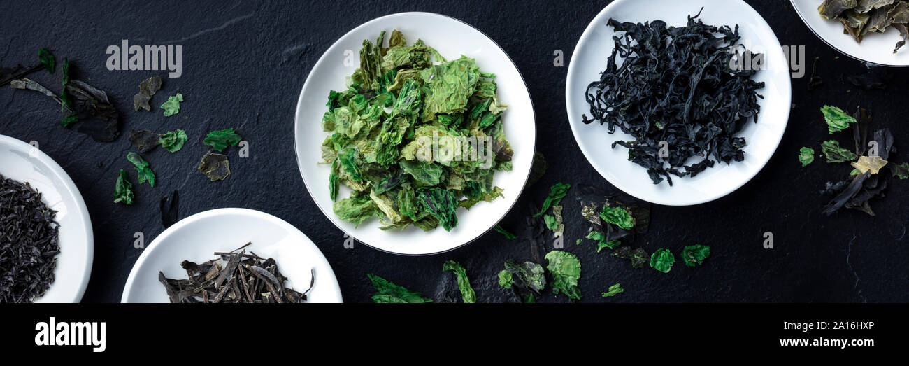 A panorama of various dry seaweed, sea vegetables, shot from above on a black background Stock Photo