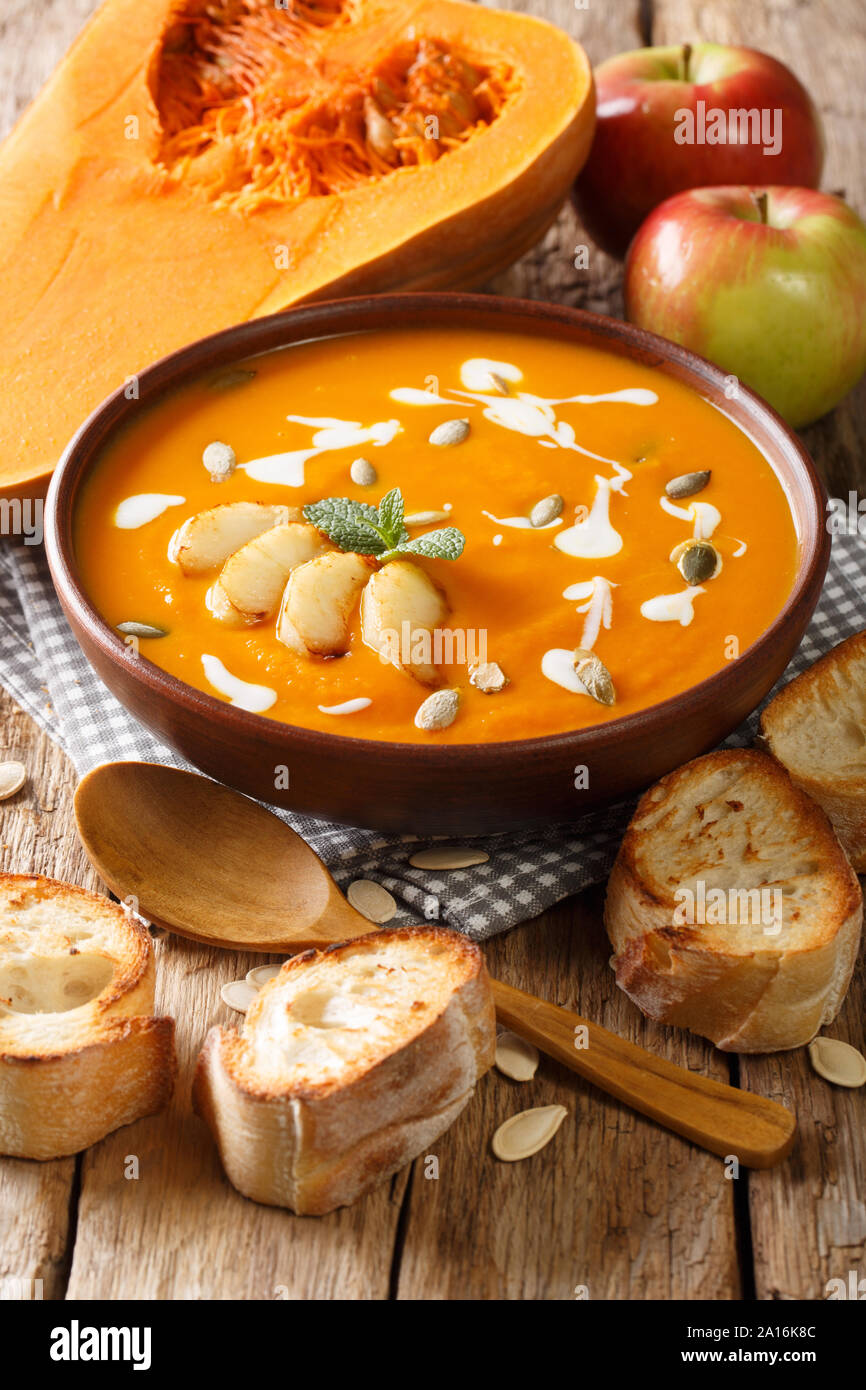 Pumpkin and apple soup with seeds, yogurt surrounded by ingredients close-up on the table. vertical Stock Photo