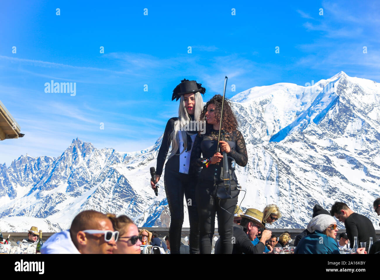 Artists perform in an after ski event, with snow capped Mont Blanc in the back on a sunny day. La Folie Douce Saint Gervais Restaurant Chamonix. Stock Photo