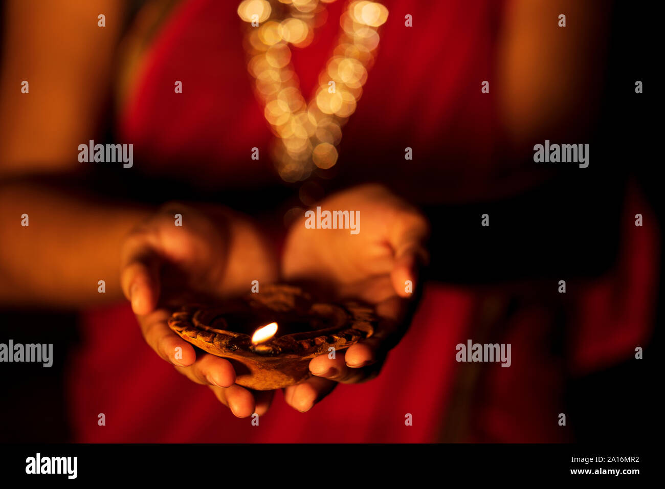 Happy Diwali - A beautiful woman or housewife holding a diya. Newly wed bride wearing traditional saree & jewellery with terracotta oil lamp on her ha Stock Photo