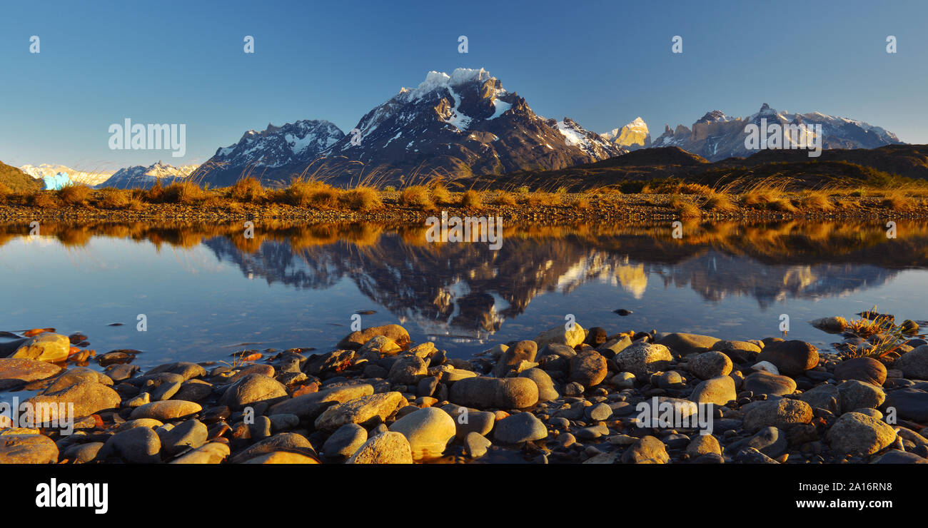 Panoramic reflection of Cuernos and Torres del Paine peaks in Lago Grey with an iceberg at Sunrise, Torres del Paine national park, Patagonia, Chile. Stock Photo