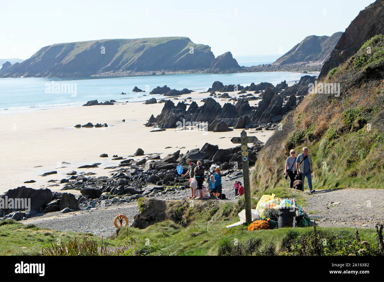 Rubbish collection and plastic collected from the beach at Marloes Sands & family walking on Wales Coastal Path Pembrokeshire UK  KATHY DEWITT Stock Photo