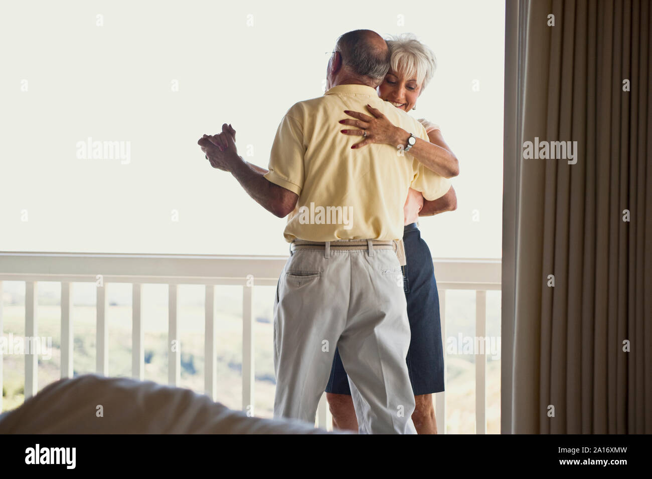 Senior couple dancing together on their balcony. Stock Photo