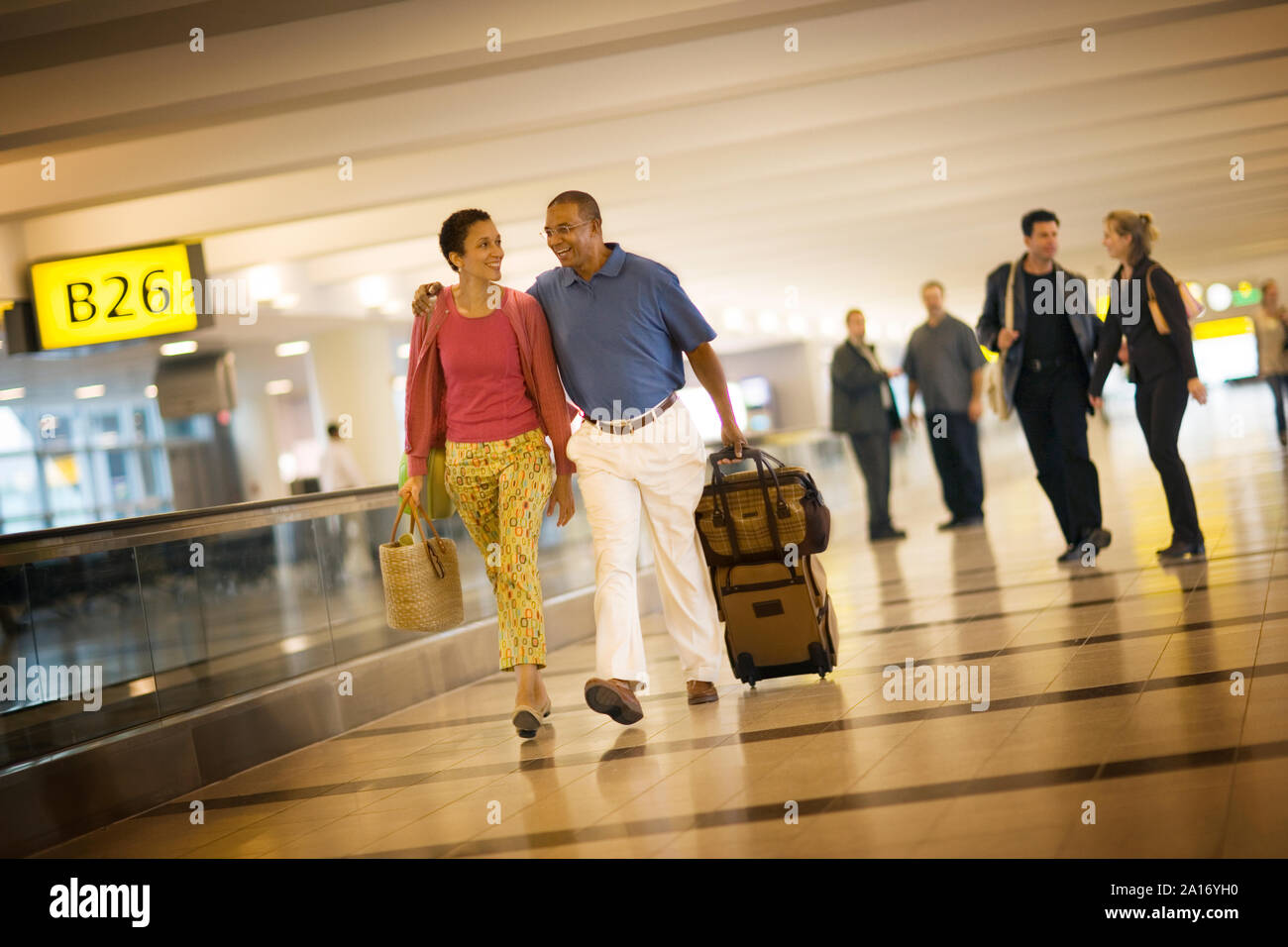 Mid-adult couple walking through an airport terminal Stock Photo - Alamy