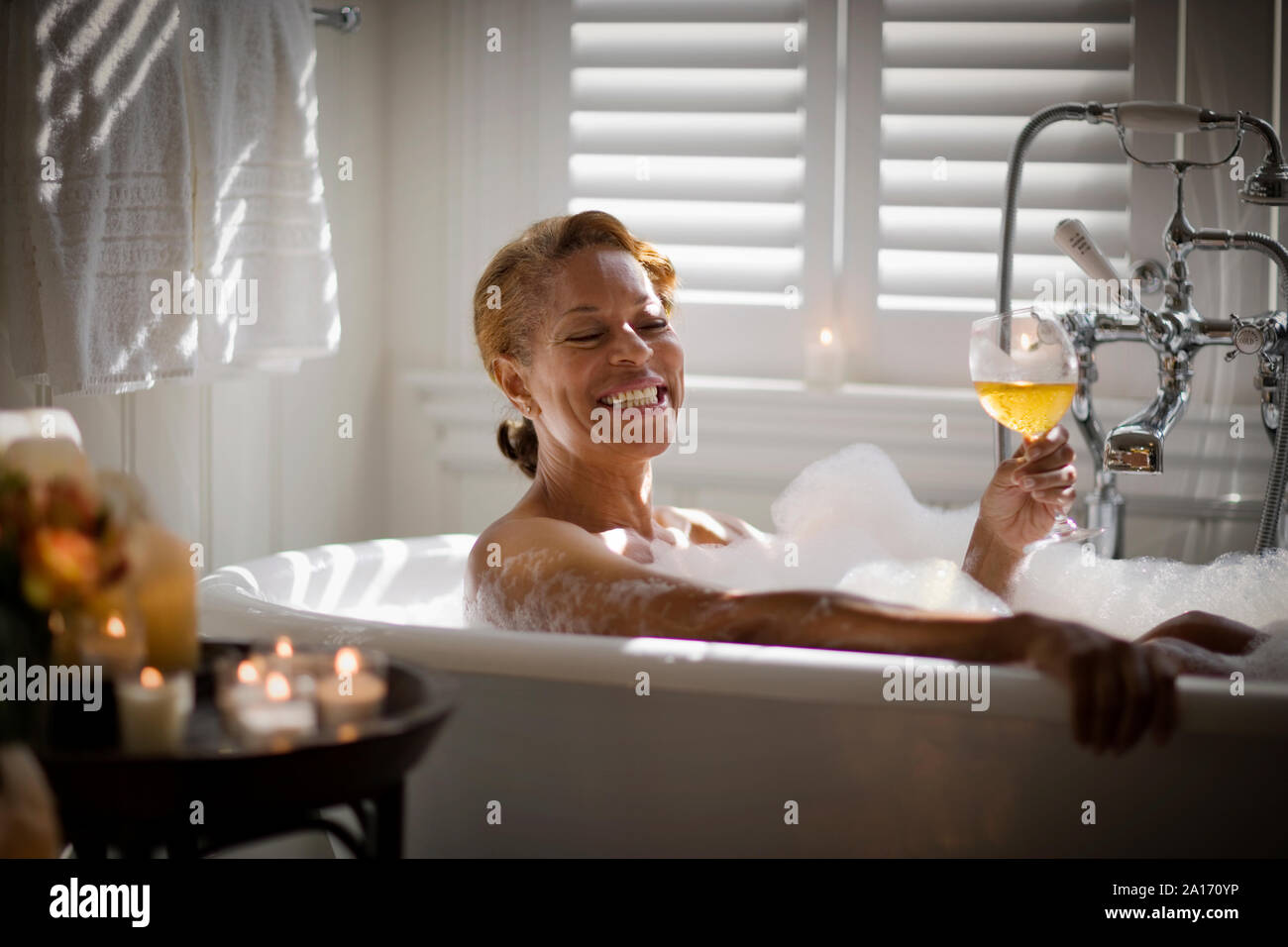 https://c8.alamy.com/comp/2A170YP/mid-adult-woman-relaxing-in-a-bubble-bath-with-a-glass-of-wine-and-surrounded-by-candles-2A170YP.jpg