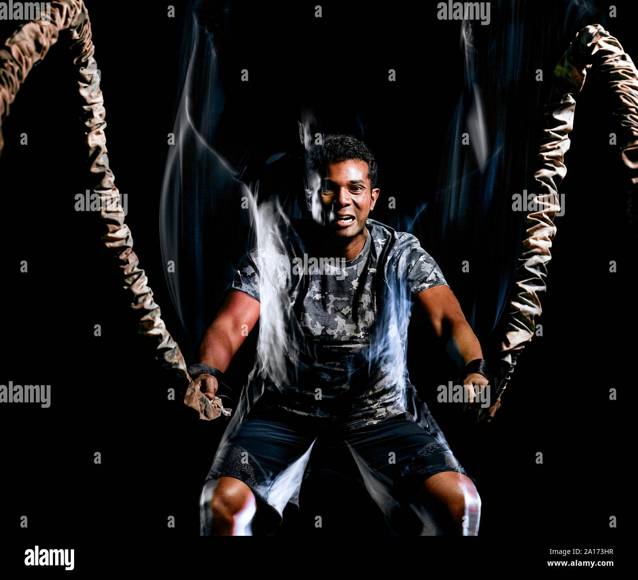 one afro american man exercising boot camp fitness ropes exercises isolated on black background with light painting speed effect Stock Photo