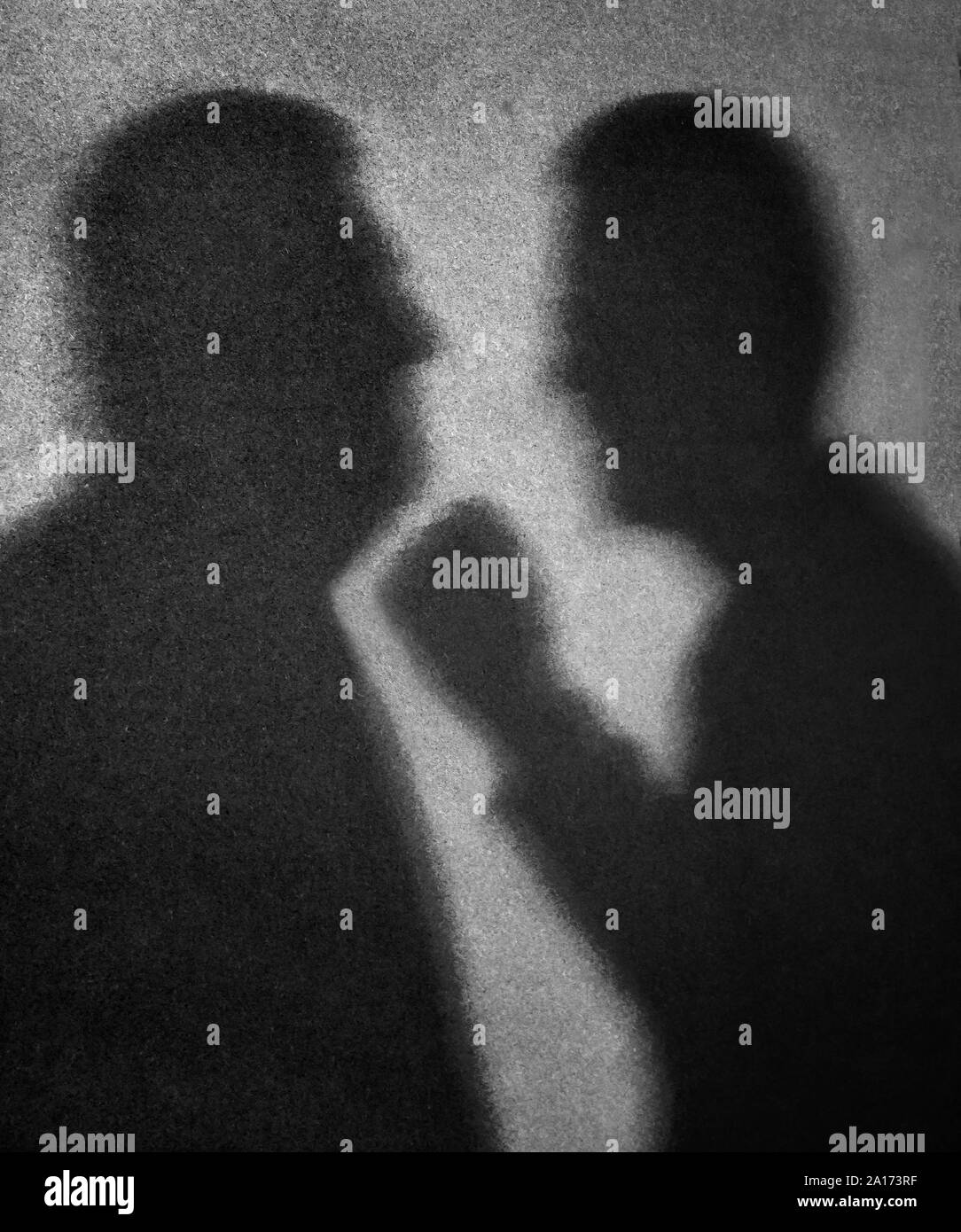 The shadows of two men facing each other with one man about to punch the other under the chin with a clenched fist Stock Photo