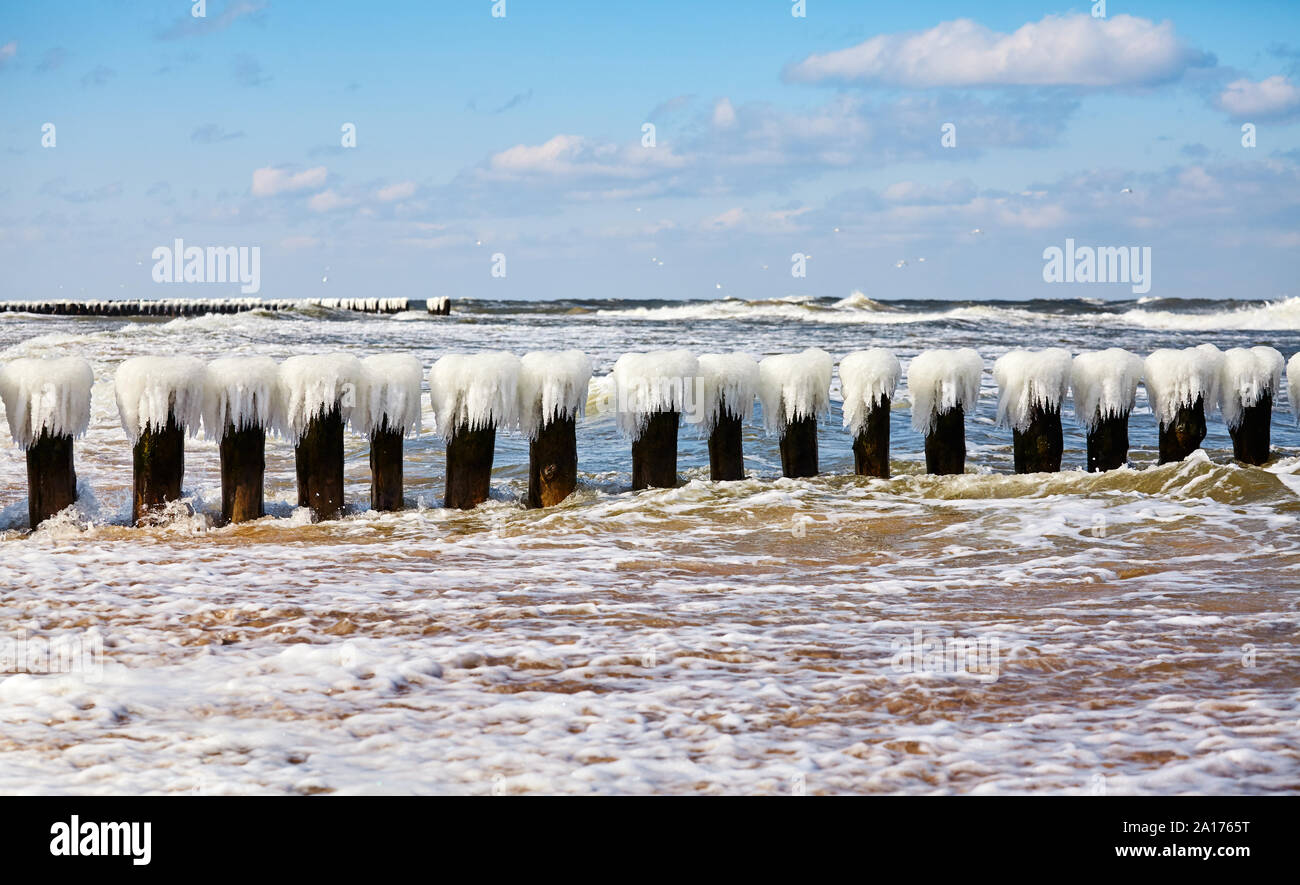 An icy wooden breakwater on a sunny day. Stock Photo