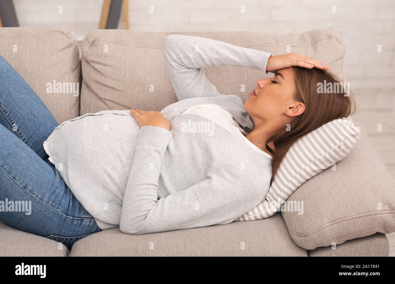 Pregnant woman feeling bad lying on couch at home Stock Photo Alamy