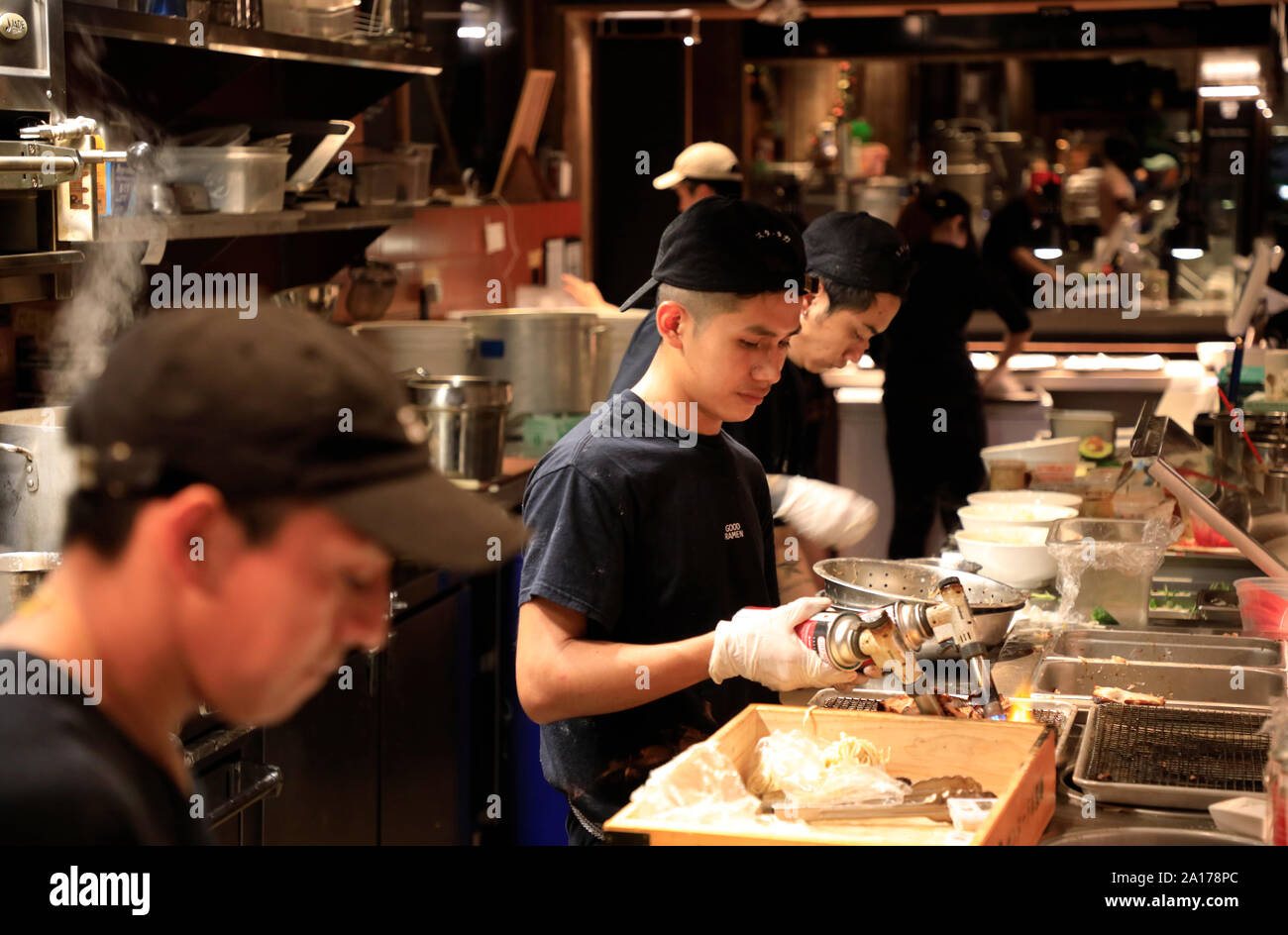 Cooks working in the open kitchen of Mr.Taka Ramen Japanese Soup Bowls in Time Out Market New York in DUMBO Brooklyn.New York City.USA Stock Photo