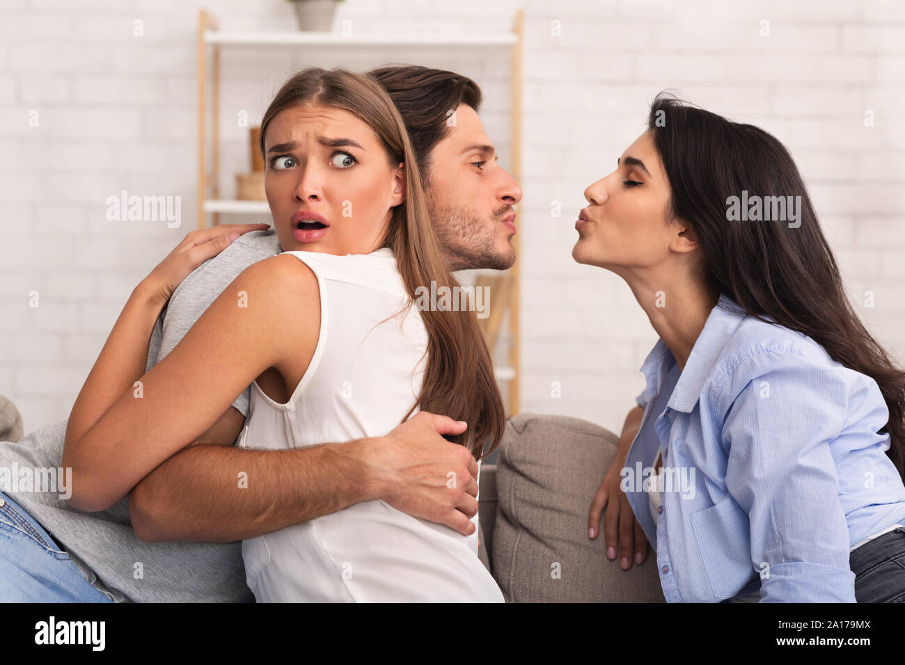 Cheating Boyfriend Kissing Girl Hugging His Girlfriend On Couch Indoor Stock Photo
