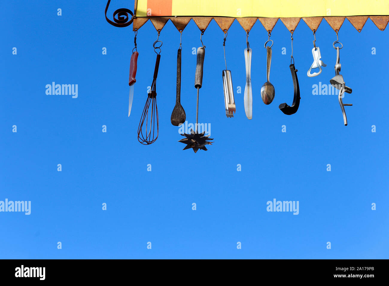 objects, utensils and cutlery hanging on yellow stand on blue background Stock Photo