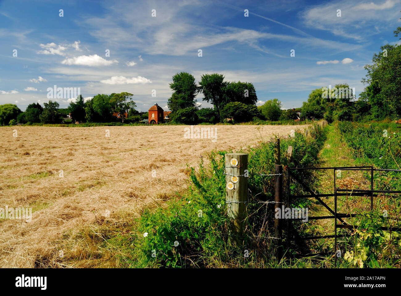 A metal kissing gate at a public footpath junction beside a large field. Stock Photo