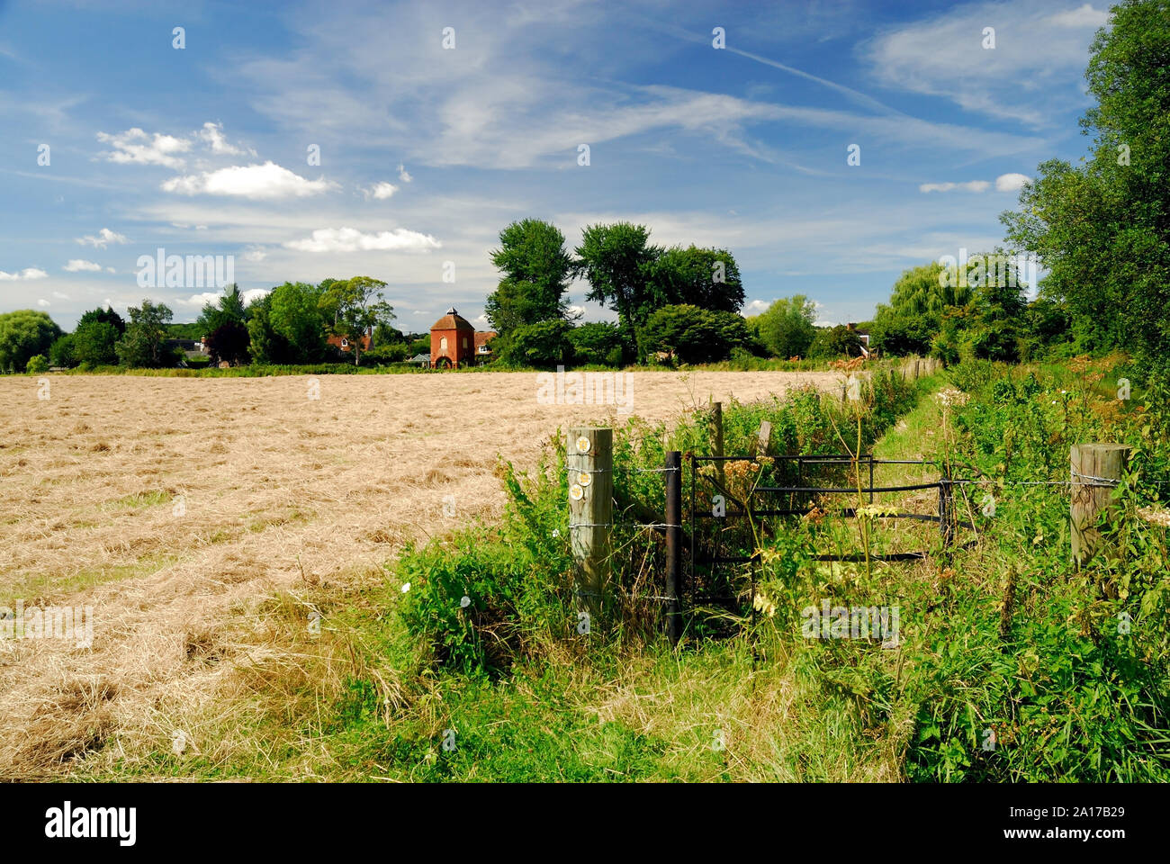 A metal kissing gate at a public footpath junction beside a large field. Stock Photo