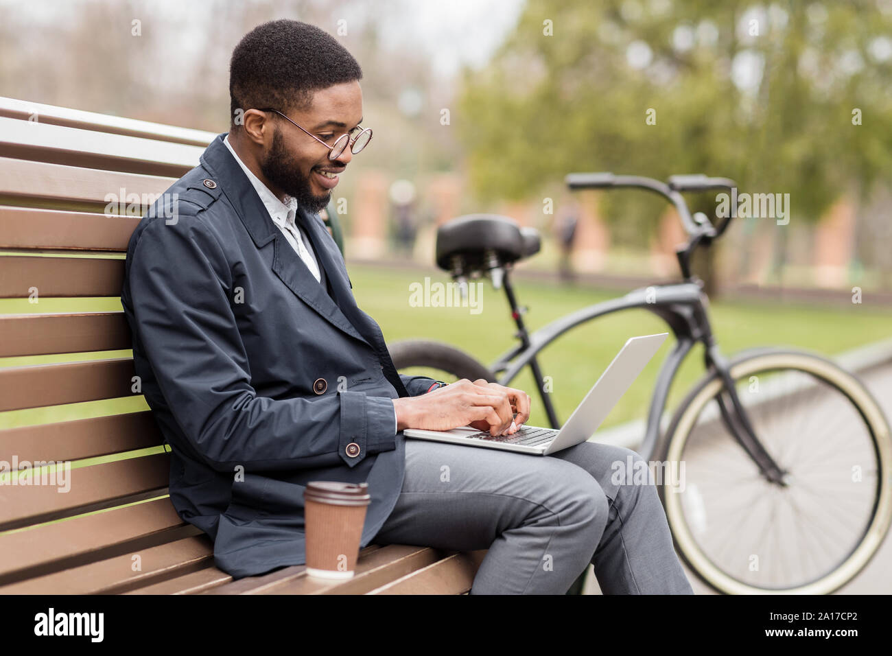 Freelancer working on laptop in park on bench Stock Photo