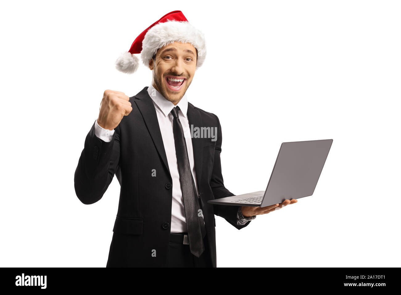 Young professional man in a suit with a Santa Claus hat gesturing happiness and holding a laptop computer isolated on white background Stock Photo