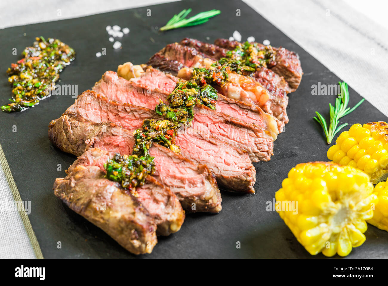 Sliced medium rib eye beef steak meat with chimichurri on black ...