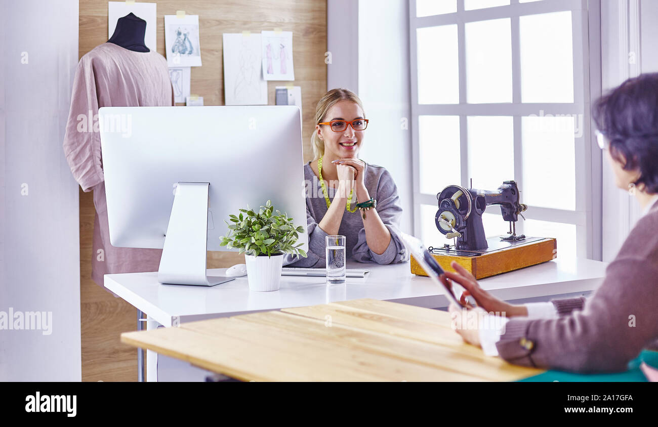 pretty dressmaker showing a new design to her client Stock Photo - Alamy