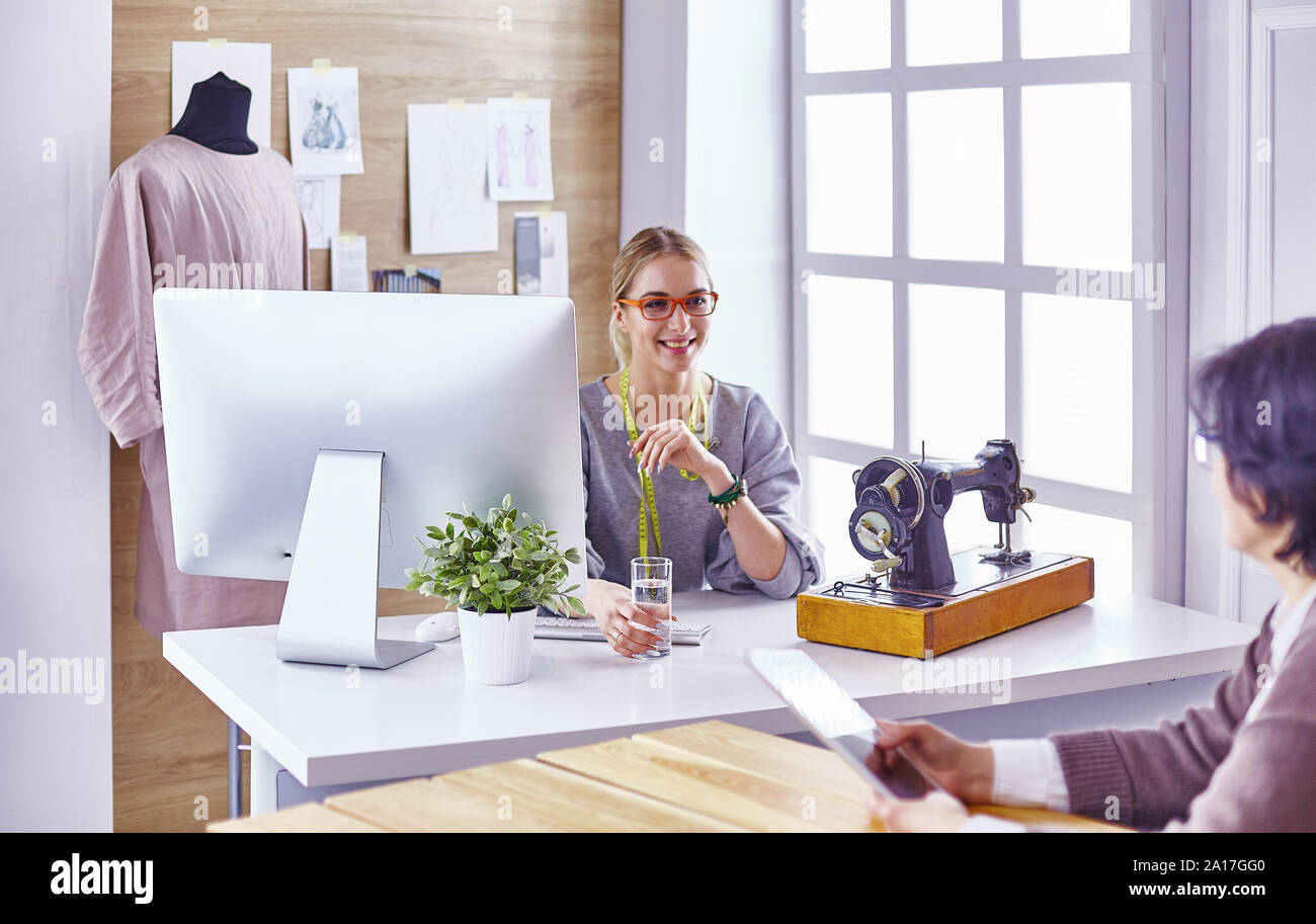 pretty dressmaker showing a new design to her client Stock Photo - Alamy