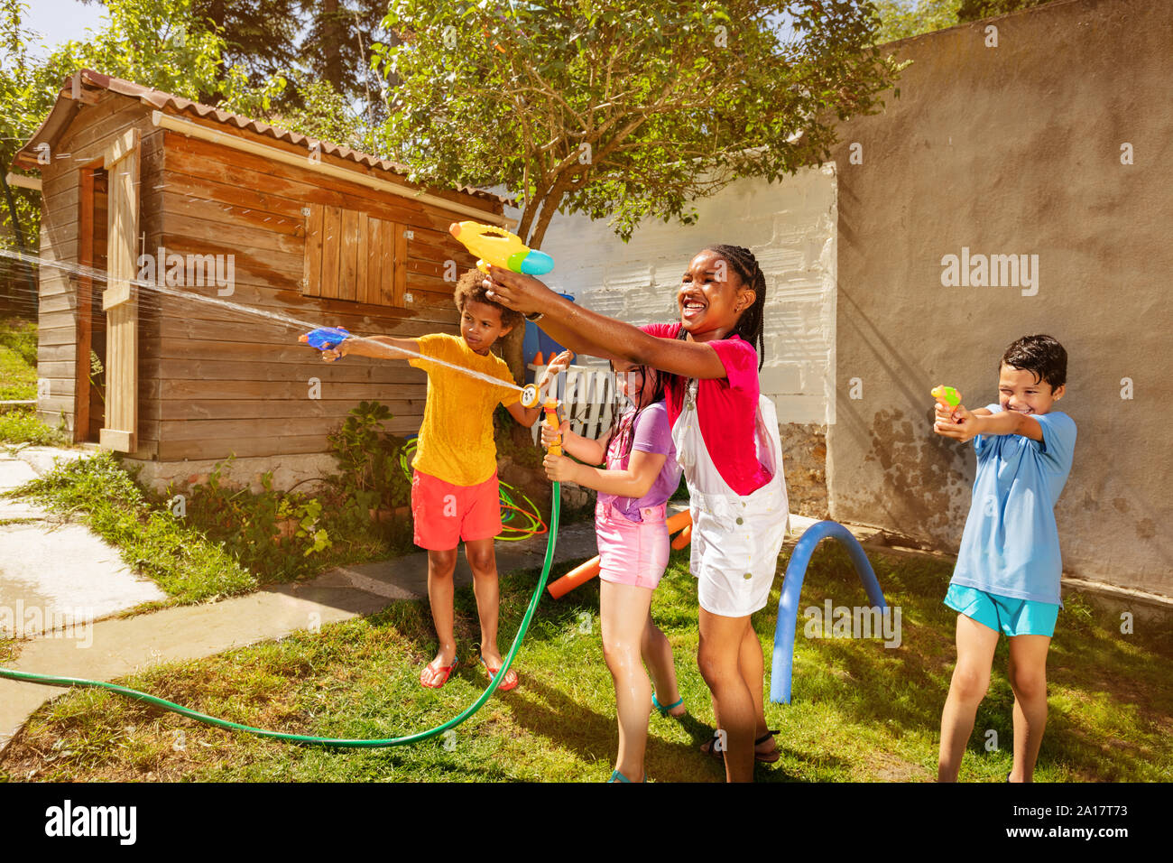 Water pistol fight game with group of diverse little kids shoot guns in