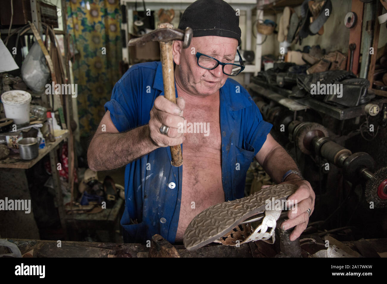 Cobbler hammering a sandal sole at shoe repairing store Stock Photo