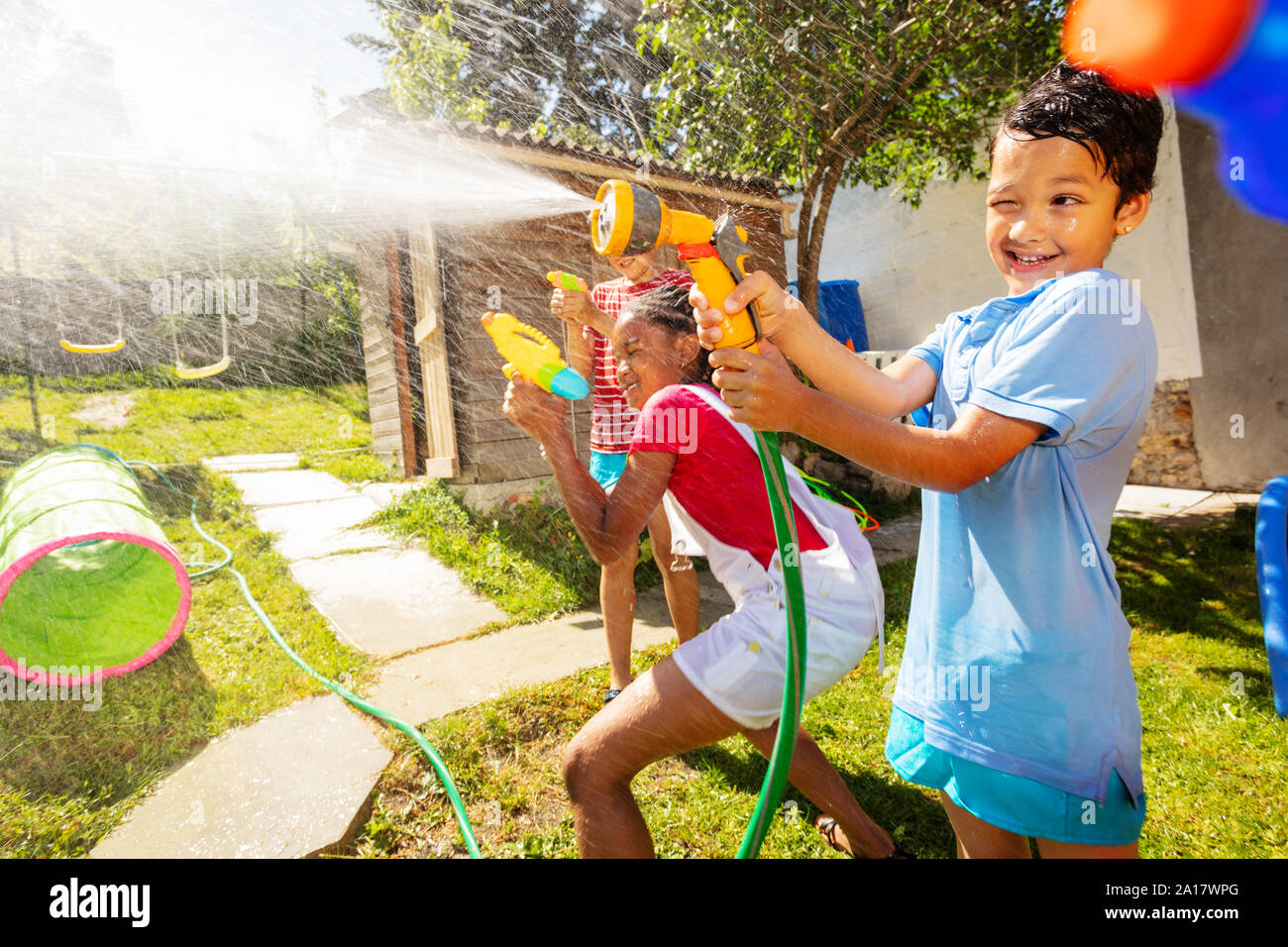 Fun active game of water gun fight with boy showing grimace strong  expression holding garden hose sprayer Stock Photo - Alamy