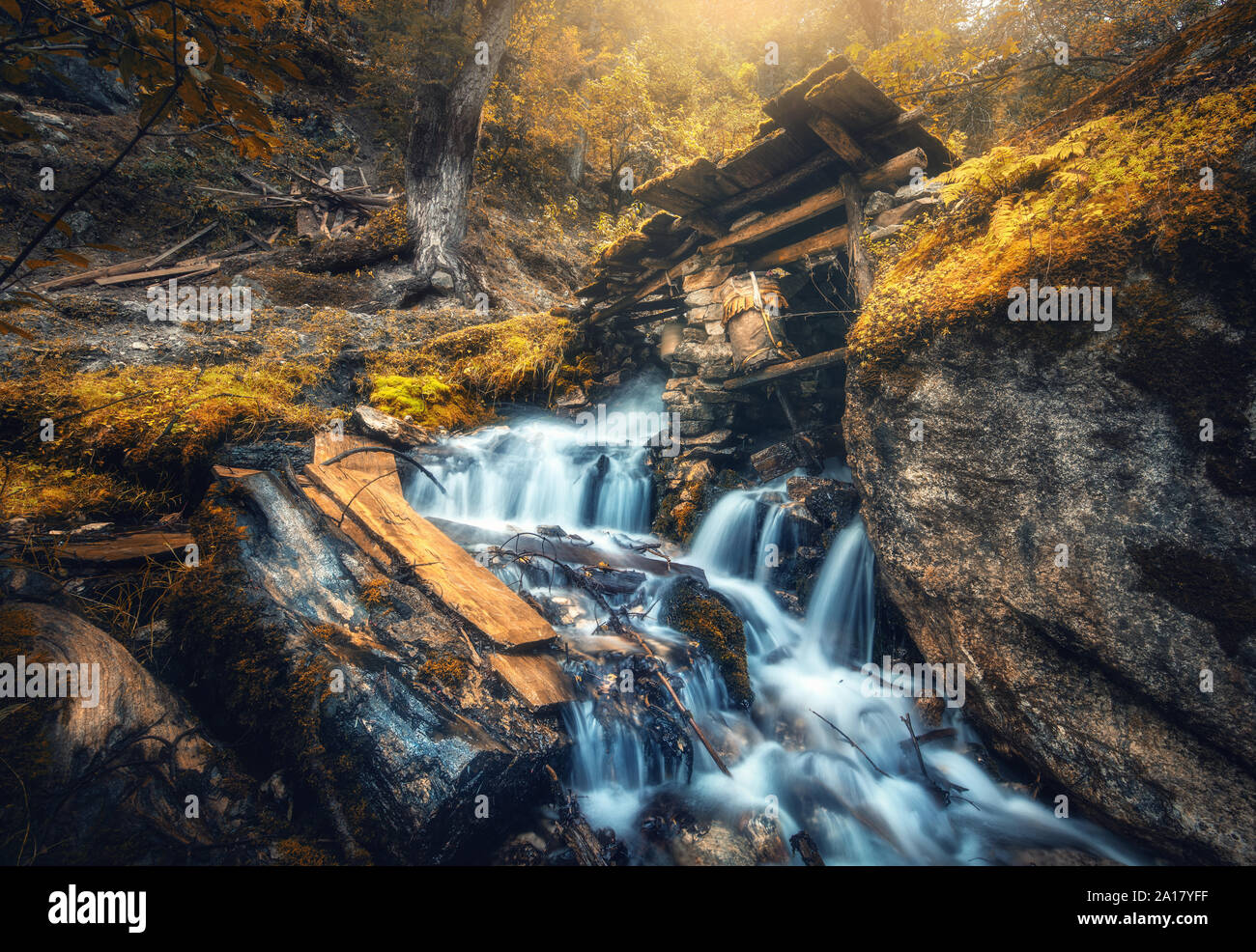 Stony well in colorful orange forest with little waterfall Stock Photo