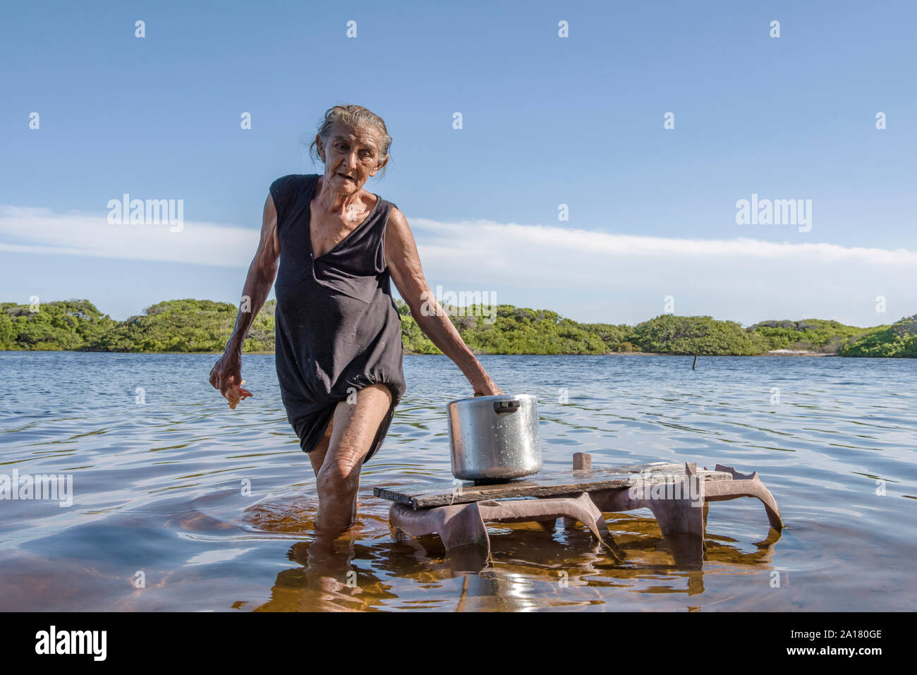 Old woman washing pan in the river of Lencois Maranhenses Stock Photo