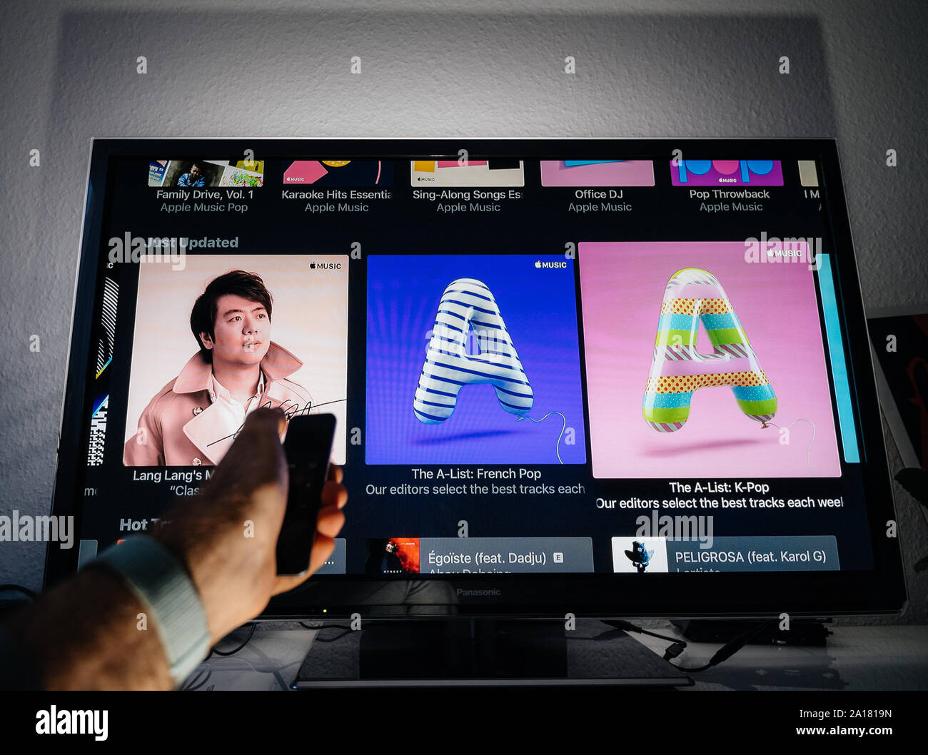 De layout Blazen dans Paris, France - Circa 2019: Man hand holding remote control of Apple TV in  front of Panasonic Plasma tv set in living room with Lang Lang new album, French  pop and K-Pop