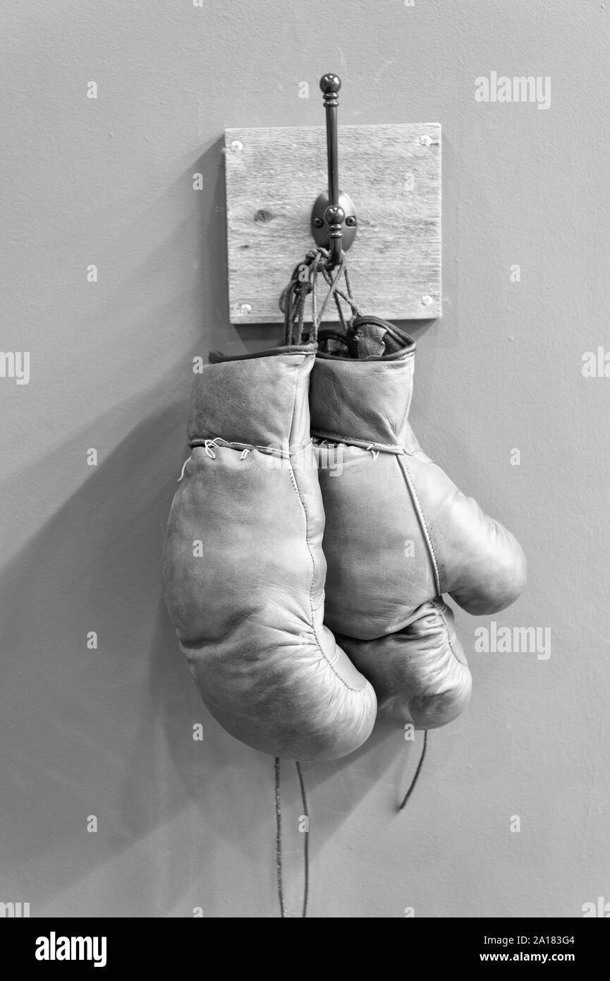retro boxing gloves. vintage sport equipment. boxing concept. old boxing gloves on hanger. history of sport. worn gloves. stamina. boxing fight club. Sport success. Vintage gloves hang on hook. Stock Photo