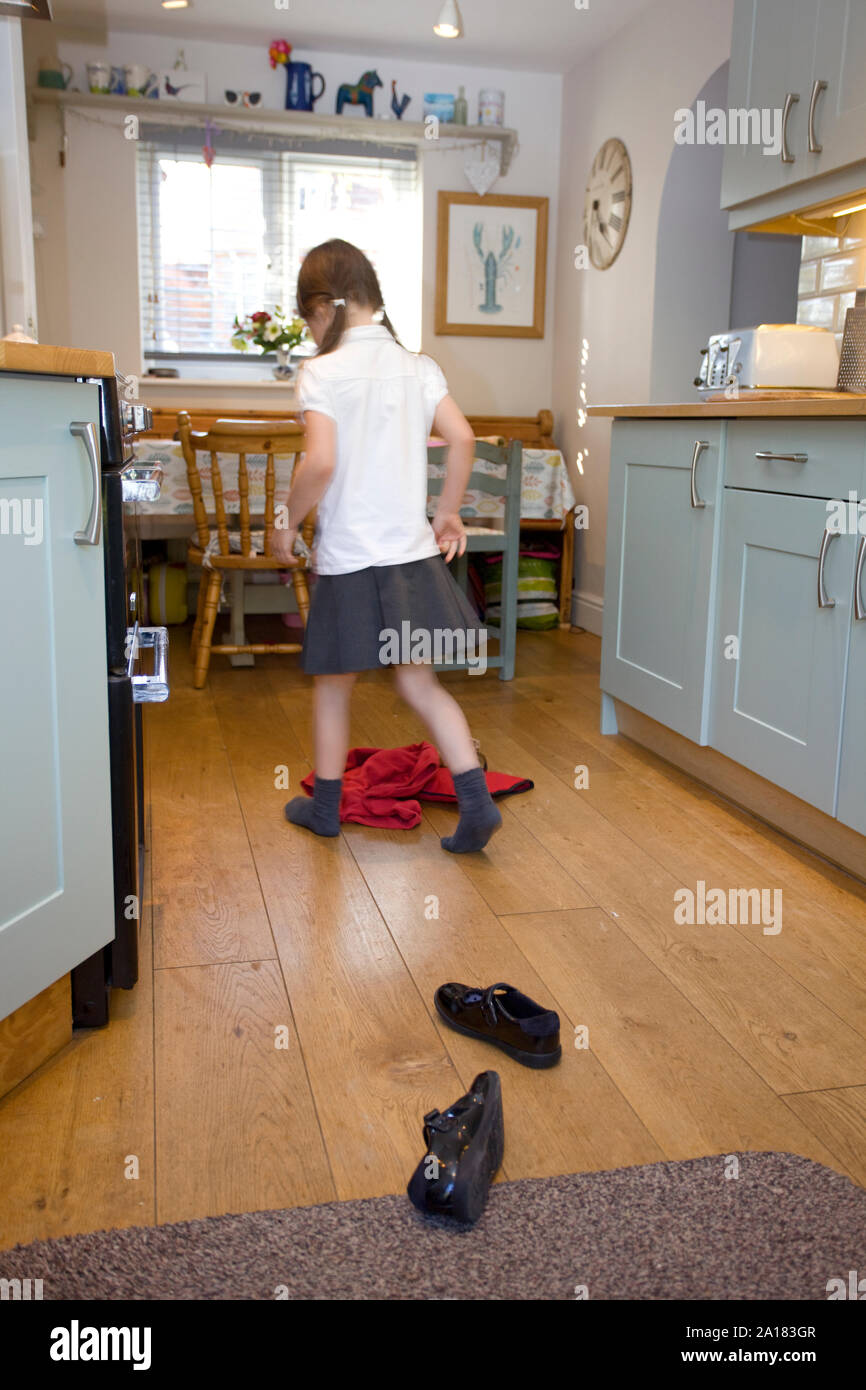 Toung girl walking in from school dropping bags Stock Photo