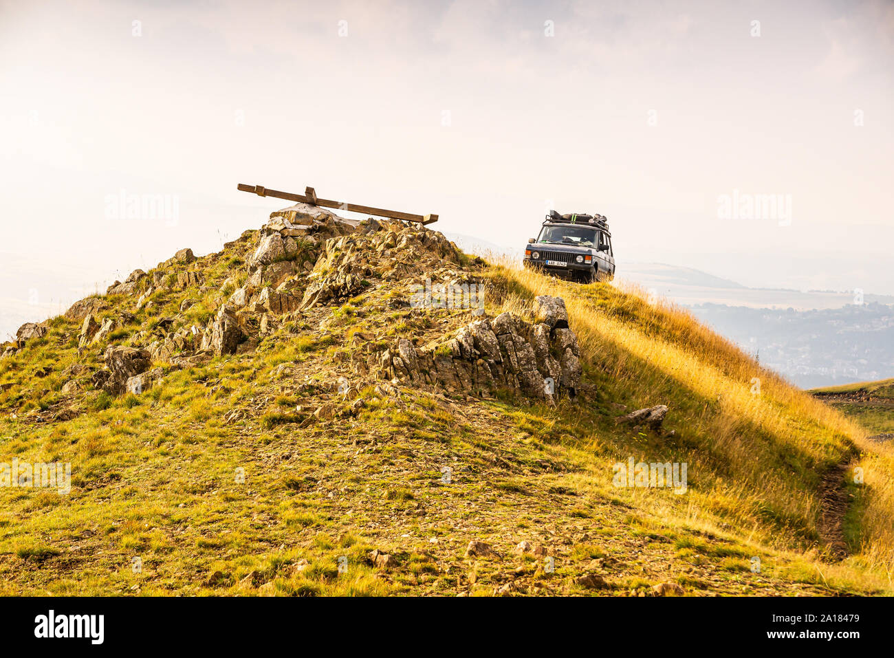 Zlatibor, Serbia - July 30, 2019. Vintage off road car on the top of the golden hill with lying cross on the top Stock Photo